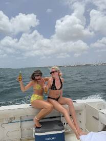 Two friends enjoy a lively boat party, celebrating with drinks and laughter on the water — a perfect day for fun in the sun.