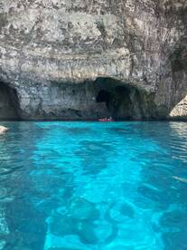 A stunning view of kayakers exploring a beautiful cave surrounded by crystal-clear turquoise waters — a perfect adventure for nature lovers.