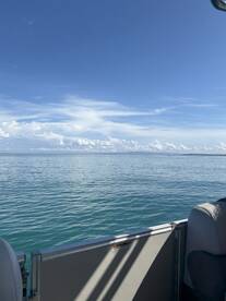 A serene view from the side of a boat, showcasing calm waters and a clear blue sky — perfect for a day of relaxation on the water.