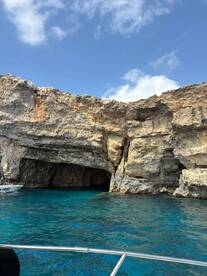 A stunning view of a rocky coastline and cave entrance, captured from a boat in crystal-clear waters — perfect for exploring natural wonders on a boating adventure.
