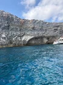 A stunning view of a rocky coastline with a boat anchored nearby, showcasing the natural beauty of the area — perfect for sightseeing and exploration.