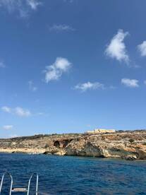 A stunning view of a rugged coastline with clear blue waters, showcasing the natural beauty of the area — perfect for exploring by boat.
