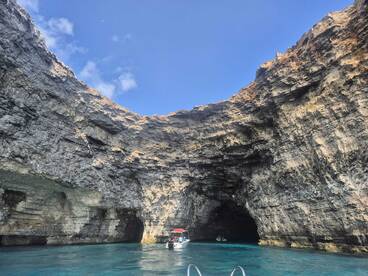 A stunning view of a boat navigating through a picturesque cave, showcasing the dramatic rock formations and clear turquoise waters — a perfect destination for adventure seekers.
