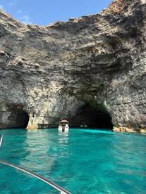 A stunning view of boats navigating through a picturesque cave with vibrant turquoise waters, perfect for exploring natural wonders on a boating adventure.