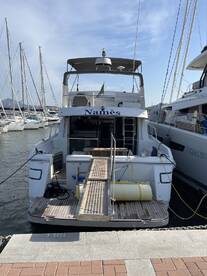 A clear view of the back of a yacht named 'Namès' docked at the marina, showcasing its structure and design against a backdrop of other boats.