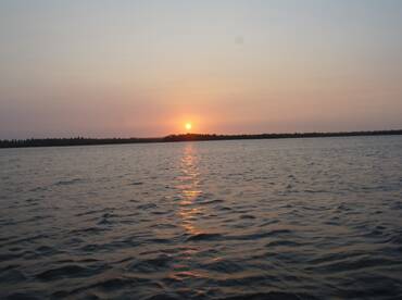 A serene sunset over calm waters, showcasing the beauty of nature — perfect for peaceful evening boat rides.