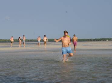 A lively group enjoys a fun day at the beach, splashing in the water and soaking up the sun during a sandbar stop.