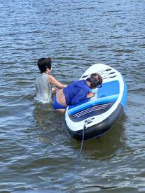 Two children enjoy paddleboarding in the water, showcasing a fun and active day on the water.