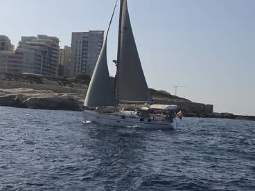 A sleek sailboat navigates the waters near a coastal city, showcasing the perfect blend of adventure and urban scenery.