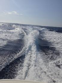 A stunning view of the boat's wake as it glides through the open water, showcasing the beauty of a day on the sea.