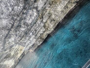 An unclear image of rocky cliffs and turquoise water, lacking identifiable features or subjects.
