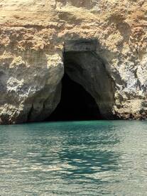 A stunning view of a coastal cave entrance surrounded by clear turquoise waters, perfect for exploring hidden gems during a boating adventure.