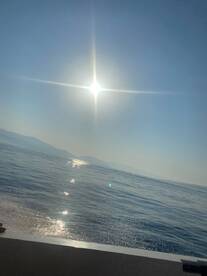 A scenic view of the sun reflecting on the water, with distant mountains visible. The image lacks clarity and focus.