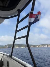 A view from the deck of a boat showcasing a flag and the serene ocean backdrop, perfect for capturing the essence of a day on the water.