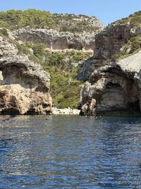 A picturesque view of a secluded beach surrounded by rocky cliffs, with people enjoying the water and sun — an ideal spot for swimming and relaxation.