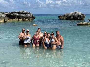 A joyful group of friends enjoys a sunny day at the beach, wading in the clear waters and celebrating together — perfect for memorable vacation moments.