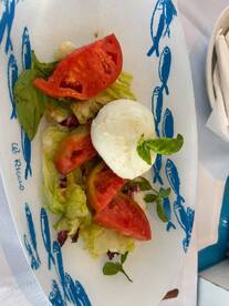 A vibrant salad featuring fresh tomatoes, lettuce, and mozzarella, perfect for enjoying on a boat trip or at a seaside restaurant.