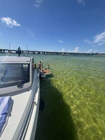 A lively group enjoys a sandbar stop, with some swimming and others relaxing on the boat — a perfect day for fun in the sun.