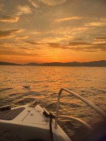 A stunning sunset view from the bow of a boat, showcasing the tranquil waters and distant mountains — perfect for evening cruises.