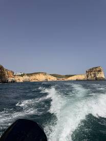 A scenic view of the coastline from a boat, showcasing stunning cliffs and clear waters — perfect for exploring beautiful destinations by sea.