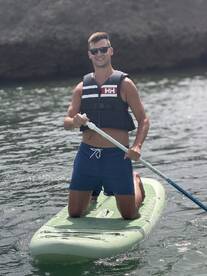 A man enjoys paddleboarding on calm waters, showcasing an active and adventurous day on the water.