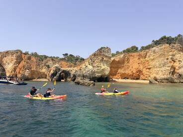 A group of kayakers paddles along a stunning coastline, surrounded by beautiful cliffs and clear waters — a perfect adventure for nature lovers.