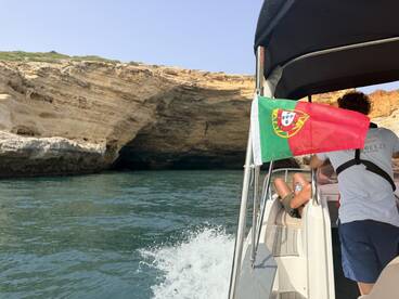 A scenic view of a boat navigating along the stunning coastline of Portugal, showcasing the natural beauty and adventure of exploring hidden caves and cliffs.