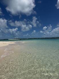 A sleek speedboat anchored on a pristine beach, surrounded by crystal-clear waters and a stunning blue sky — perfect for a day of relaxation and adventure.