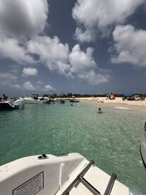 A vibrant scene at a sandbar with people enjoying the clear waters and beach, surrounded by various boats — perfect for a fun day on the water.