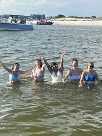 A lively group of friends enjoys a fun day swimming in the water, celebrating together under the sun — perfect for beach outings and summer adventures.