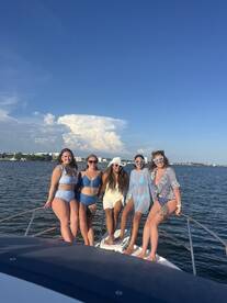A fun group of friends poses on the bow of a boat, enjoying a sunny day on the water — perfect for summer celebrations and memorable outings.