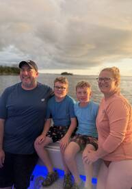 A joyful family poses together on a boat during sunset, capturing a memorable moment on the water — perfect for family outings and celebrations.