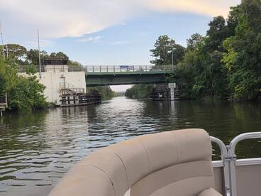 A scenic view of a waterway with a bridge overhead, showcasing the tranquility of boating through lush surroundings.