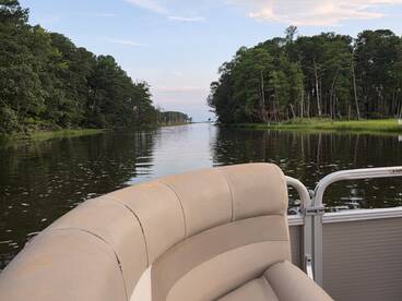 A cozy view from the seating area of a pontoon boat, showcasing a serene waterway surrounded by lush greenery — perfect for relaxing outings on the water.