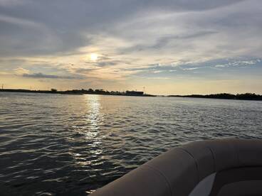 A serene sunset view from a boat, showcasing the tranquil waters and distant shoreline, perfect for evening cruises.