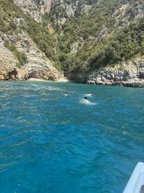 Swimmers enjoy the crystal-clear waters near a stunning rocky coastline, showcasing the beauty of outdoor adventures on the water.