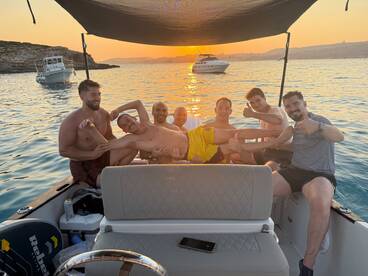 A lively group of friends enjoys a sunset celebration aboard a boat, showcasing the perfect atmosphere for fun and camaraderie on the water.