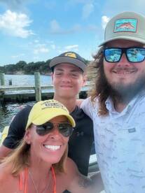 A joyful group poses for a selfie by the water, capturing a fun moment during their boating adventure. Perfect for family outings and memorable trips.