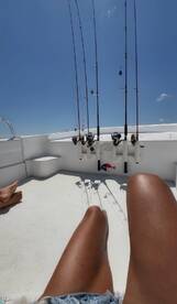 A view of fishing rods set up on a boat, with a person's legs visible, perfect for a day of fishing on the water.