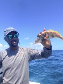 A man proudly holds up his catch while fishing in the ocean, showcasing the thrill of a successful day on the water.
