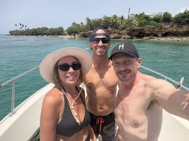 A cheerful group enjoys a sunny day on the boat, capturing a fun selfie against a beautiful tropical backdrop — perfect for memorable adventures on the water.