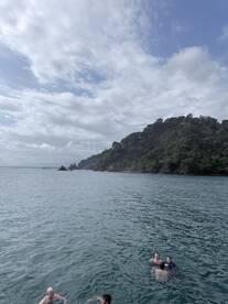 A group of friends enjoys a refreshing swim in the clear waters near a lush coastline, perfect for a fun day out on the water.