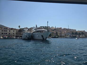 A stunning view of two luxurious yachts docked in a picturesque harbor, showcasing the charm of coastal architecture and clear blue waters.