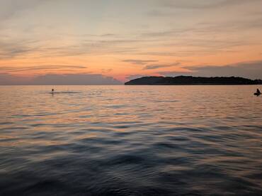 A serene sunset view with a person enjoying the water, creating a picturesque scene perfect for evening boat trips or romantic getaways.