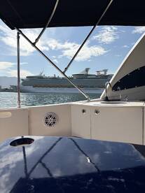 A view from inside a boat showcasing the helm and a large cruise ship in the background, perfect for those looking to explore the waters in comfort.