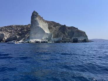 A stunning view of a sailboat navigating past dramatic coastal cliffs, showcasing the natural beauty of the island — perfect for sailing adventures and scenic tours.