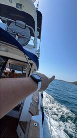 A hand gestures towards the scenic view while aboard a boat, capturing the essence of a fun day on the water with family.