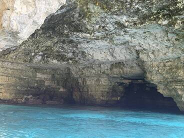 A stunning view of a cave along the coastline, with crystal-clear turquoise waters reflecting the natural beauty of the surroundings — perfect for eco tours and exploration.
