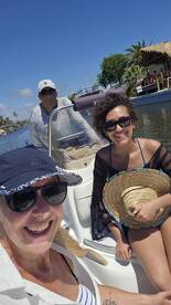 A cheerful group enjoys a sunny day on a boat, capturing the moment with smiles as they navigate through a scenic waterway.