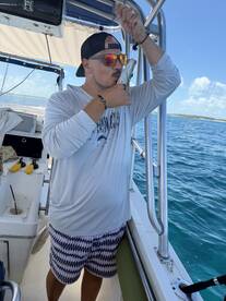 A man joyfully kisses his catch aboard a boat, showcasing the thrill of fishing in the open ocean — a perfect moment for fishing enthusiasts.